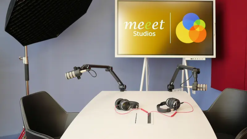 Podcast Set Konrad 2 oM Totale 800 Podcast-Set im Studio Konrad bei Meeet Studios in Berlin Neukölln: Platz für zwei Personen am Tisch vor einem Monitor mit Logo